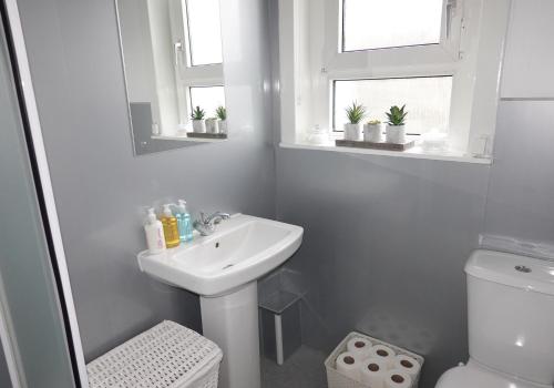 Baño blanco con lavabo y aseo en Welsh Drive Apartment by Klass Living Blantyre, en High Blantyre
