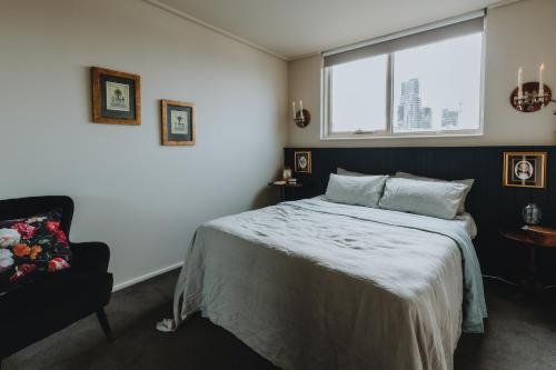 a bedroom with a bed and a window and a chair at Elegant apartment with balcony and free parking in Melbourne