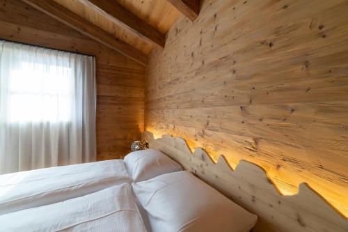 a bedroom with wooden walls and a bed with white pillows at Chalet Selun in Wildhaus