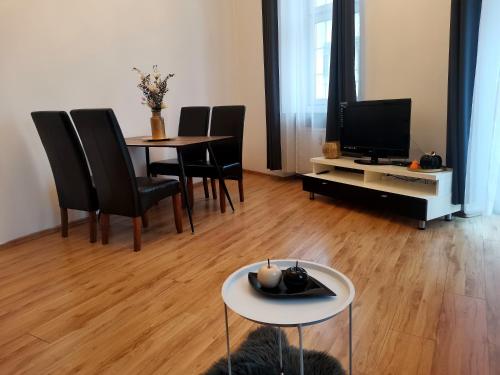 salon ze stołem, krzesłami i telewizorem w obiekcie Apartament na Rynku w Gnieźnie w Gnieźnie