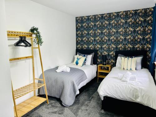 1 dormitorio con 2 camas y pared con papel pintado en Elmbank Avenue House by Klass Living Uddingston, en Uddingston