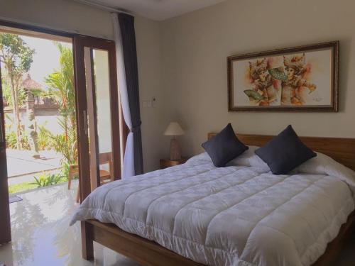 a bedroom with a large bed and a sliding glass door at Londo House in Ubud