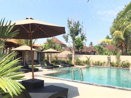 a swimming pool with umbrellas and chairs next to a resort at Londo House in Ubud
