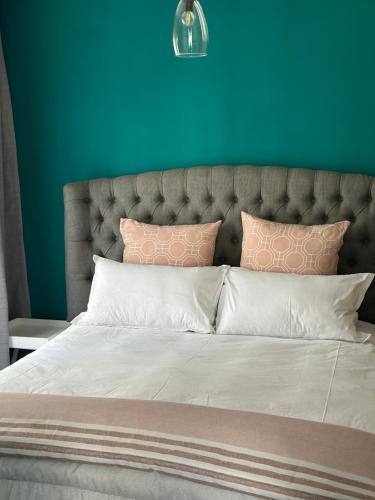 a bed with pink and white pillows and a blue wall at Cosy Waterfall Midrand Apartment in Midrand