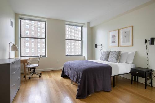 a bedroom with a bed and a desk and two windows at Back Bay 1br w gym wd close to garden BOS-942 in Boston