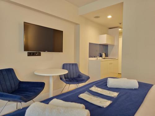 Zimmer mit einem Bett mit blauen Stühlen und einem TV in der Unterkunft ORBI Sea Breeze ApartHotel in Batumi