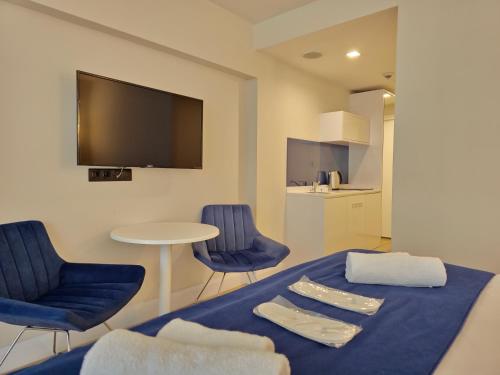 a room with a bed with blue chairs and a tv at ORBI Sea Breeze ApartHotel in Batumi