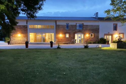 un grand bâtiment en briques avec une pelouse devant lui dans l'établissement Les Maisons de Ronsac : lieu idéal pour vos fêtes, à Saint-Pierre-de-Lages