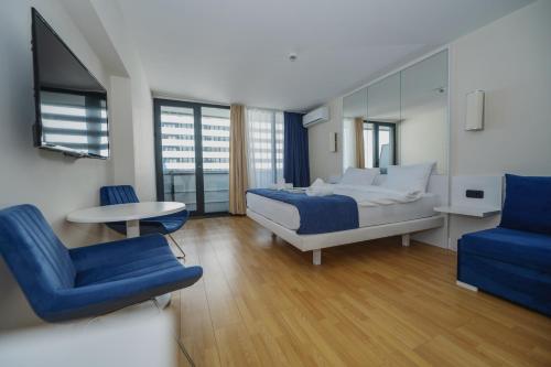 a bedroom with a bed and a table and a chair at ORBI Sea Breeze ApartHotel in Batumi