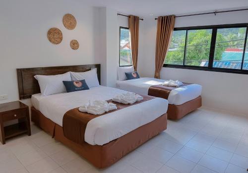 a hotel room with two beds and a window at RoomQuest Kalim Beach in Patong Beach