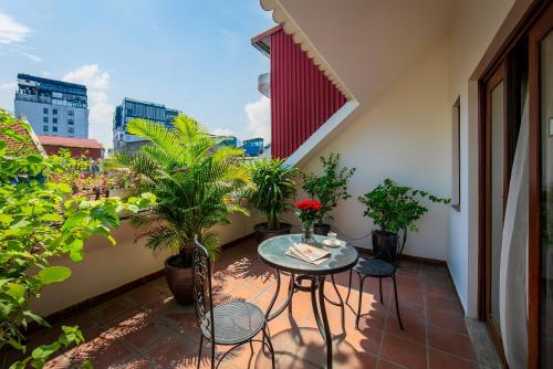 einen Balkon mit einem Tisch, Stühlen und Pflanzen in der Unterkunft Oriental Suites Hotel & Spa in Hanoi