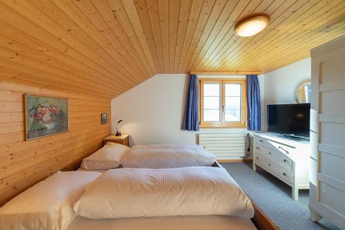 a bedroom with three beds and a television in it at Steirüti 15 in Wildhaus