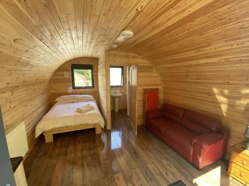 Habitación con cama y sofá en una cabaña de madera. en Woodland Pod 10 Pet Friendly en Neath