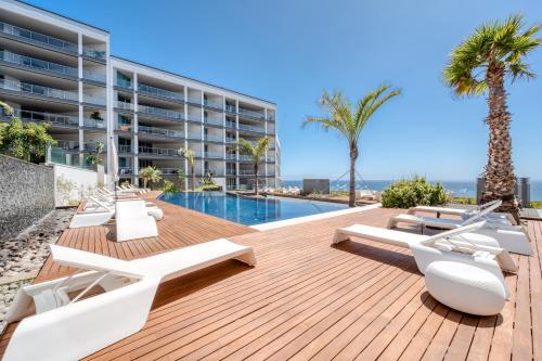 an outdoor deck with lounge chairs and a swimming pool at Suite BK - 3 Pools - Gym - AC - Huge Balcony in Funchal