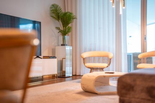 a living room with two chairs and a tv at Suite BK - 3 Pools - Gym - AC - Huge Balcony in Funchal