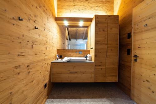 a wooden bathroom with a sink and a mirror at Chalet Zuestoll in Wildhaus