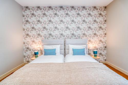 a bedroom with a large bed with two blue pillows at Suite BK - 3 Pools - Gym - AC - Huge Balcony in Funchal