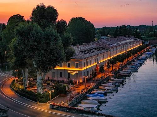 a building with umbrellas next to the water at sunset at Pavillon Suite in Peschiera del Garda