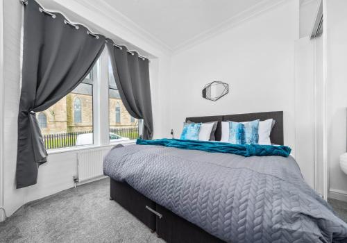 a bedroom with a bed with blue pillows and a window at Garturk Apartment by Klass Living Coatbridge in Coatbridge