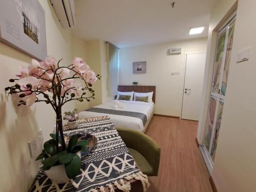 ペタリンジャヤにあるSCC HOTEL PJのベッド1台、花のテーブルが備わる小さな客室です。