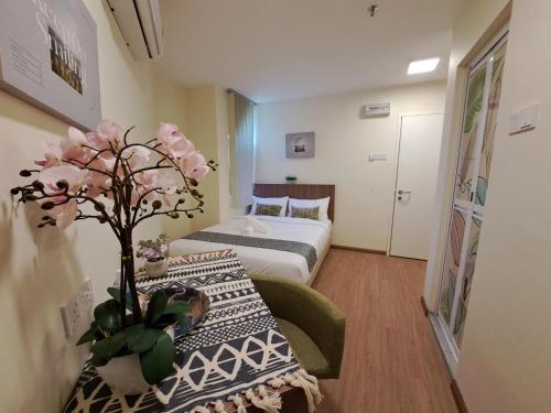 a small room with a bed and a table with flowers at SCC HOTEL PJ in Petaling Jaya