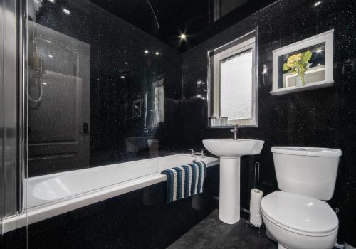 a black bathroom with a toilet and a sink at Rothesay House by Klass Living Coatbridge in Coatbridge