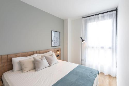 a bedroom with a bed with white sheets and a window at Be Casa - Valdebebas in Madrid