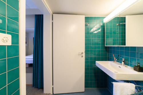 a bathroom with green tiled walls and a sink at Etienne in Wildhaus