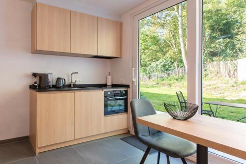 a kitchen with wooden cabinets and a table and a window at Fluithoekhoeve in Koksijde