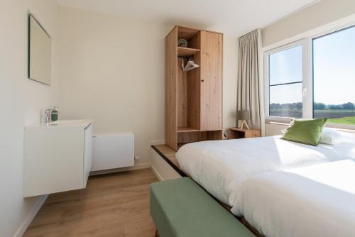 a bedroom with a large bed and a window at Fluithoekhoeve in Koksijde