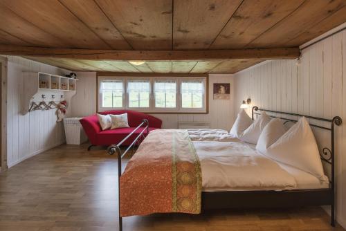 a bedroom with a large bed and a red chair at Landhuus Toggi in Alt Sankt Johann