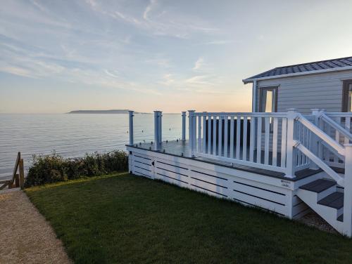 a white house with a large deck next to the water at Europa Willow Pitch 29 Creek Caravan Park in Ringstead