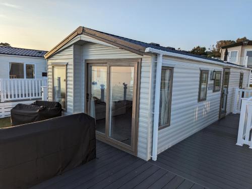 a house with sliding glass doors on a deck at Europa Willow Pitch 29 Creek Caravan Park in Ringstead