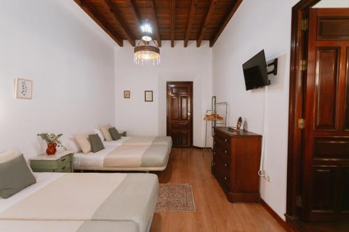Komodo Casa Maravillas Rooms في إشبيلية: غرفة نوم بسريرين وتلفزيون فيها