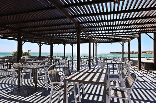 a patio with tables and chairs and the ocean at Hôtel Calipau Riad Maison d'Hôtes in Dakhla