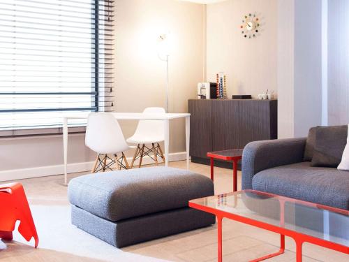 a living room with a couch and a table at Novotel Paris Rueil Malmaison in Rueil-Malmaison