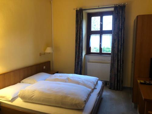 Bett in einem Schlafzimmer mit Fenster in der Unterkunft Gasthaus Klosterhof 