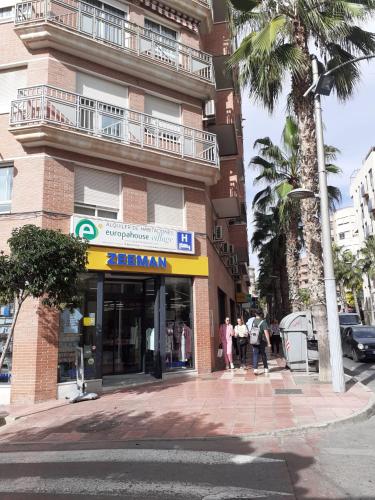 a building on a street with people walking in front of it at Europa House Village in San Vicente del Raspeig