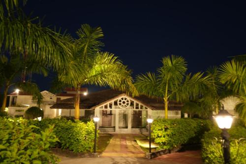 una casa con palmeras delante de ella por la noche en Beyond The Corbett Tales Resort and Spa en Rāmnagar