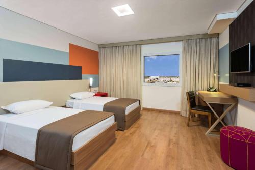 a hotel room with two beds and a desk and a television at TRYP BY WYNDHAM São Paulo Airport - Hotel de Transito Terminal 3 -Lado Ar - Área restrita á passageiros já embarcados - Piso 1 in Guarulhos