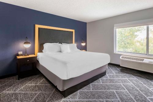 Cambria Hotel Minneapolis Maple Grove في مابل غروف: غرفة نوم بسرير ابيض كبير ونافذة