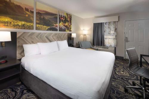 Habitación de hotel con cama blanca grande y escritorio. en Clarion Inn Biltmore Village, en Asheville