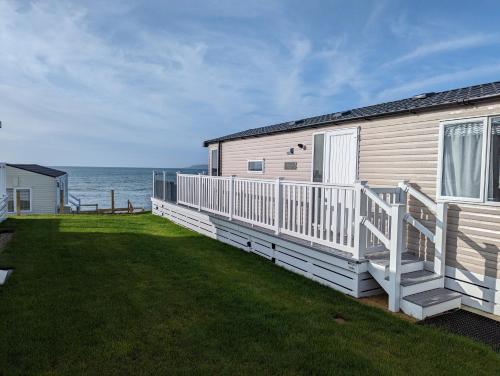 a house with a large deck and the ocean at Swift Mosselle Pitch 24 Creek Caravan Park dog friendly in Ringstead