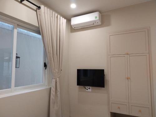 a room with a tv and a window and a curtain at An Nhiên Villa Hotel in Phú Mỹ