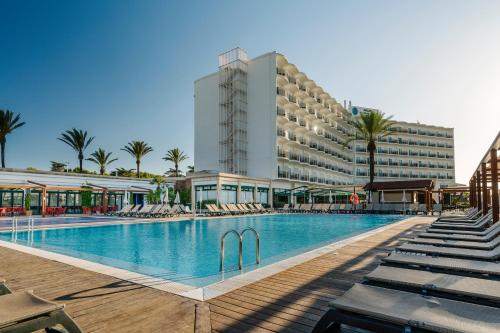un hotel con piscina frente a un edificio en Alua Illa de Menorca, en S'Algar