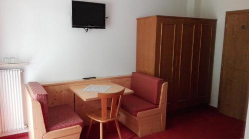 a room with a table and two chairs and a television at Garnì La Grambla in Selva di Val Gardena