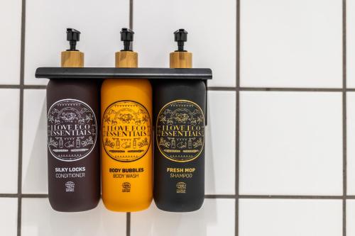 three bottles of hair products on a wall at Hotel Atlantic in Aarhus