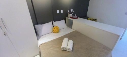 Habitación pequeña con 1 cama y 2 zapatillas blancas. en Moderno e Reformado Studio em Copacabana, en Río de Janeiro