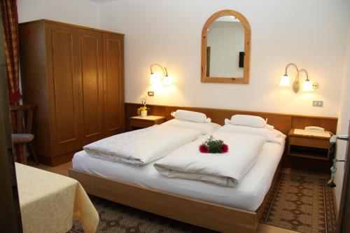 a bedroom with two beds with white blankets and a mirror at Garnì La Grambla in Selva di Val Gardena