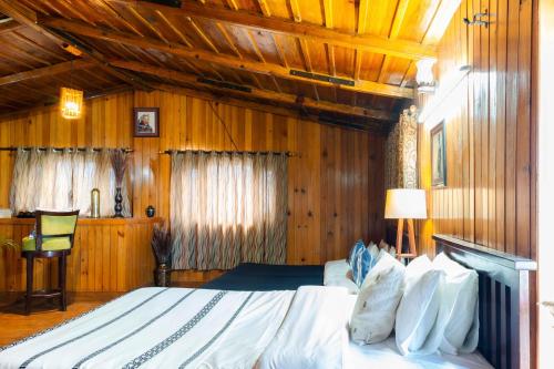 a bedroom with a large bed with wooden walls at Poetry by the Hills - House Of Hive, Ramgarh, Mukteshwar, Nainital in Rāmgarh